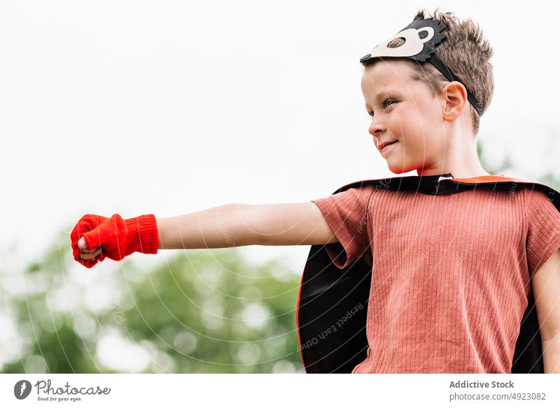 Superheld in Igelmaske im Park mit ausgestrecktem Arm mit geballter Faust Junge Mundschutz spielen Aufstieg Wochenende Tracht so tun, als ob knien Stein Klotz