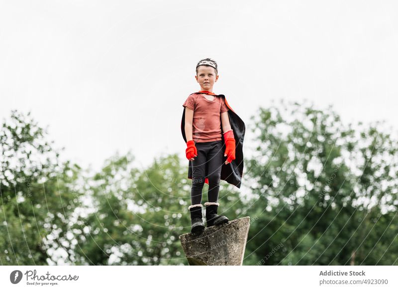 Superheld mit Igelmaske im Park Junge Mundschutz spielen Aufstieg Wochenende Tracht so tun, als ob knien Stein Klotz behüten Mut Kind Kap Kindheit Umhang Saison