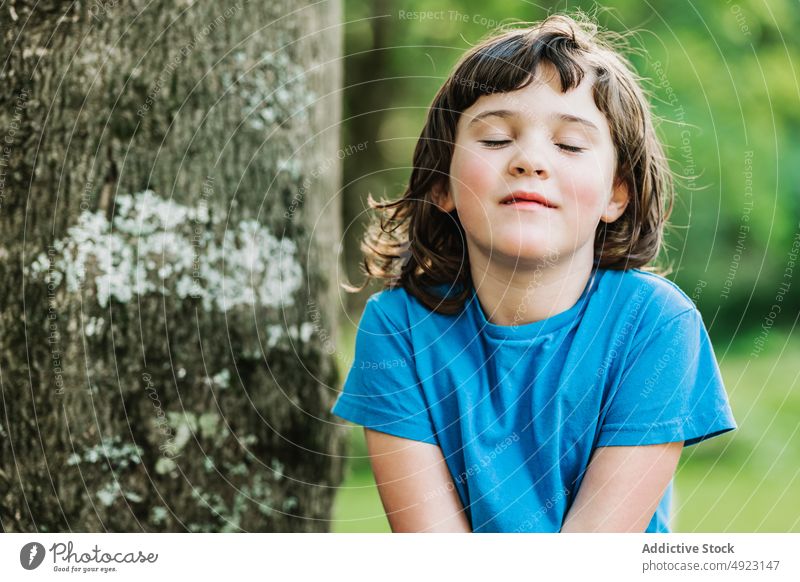 Niedliches kleines Mädchen in der Nähe des Baumes Park Lächeln Wochenende Sommer ruhen Kofferraum Augen geschlossen Porträt niedlich wenig Kind lässig T-Shirt
