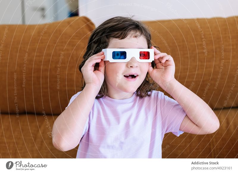 Zufriedenes Mädchen setzt zu Hause eine 3D-Brille auf 3d angezogen Film Kind amüsiert heimwärts Showtime unterhalten Fernsehen realistisch Wohnzimmer
