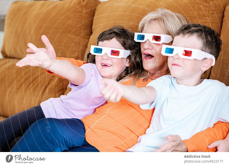 Mutter mit Kindern mit 3D-Brille schaut sich zu Hause einen Film an 3d Showtime Fernsehen unterhalten Wohnzimmer zuschauen realistisch Mädchen freie Zeit Junge