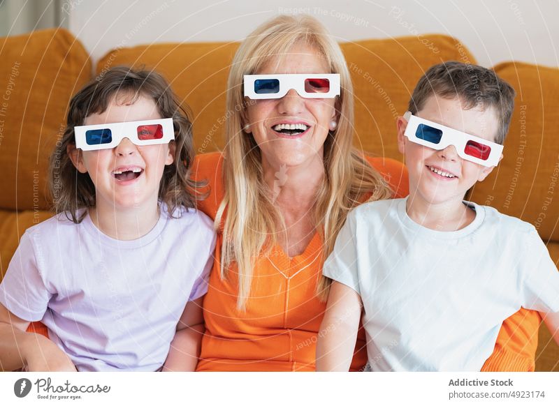 Mutter mit Kindern mit 3D-Brille schaut sich zu Hause einen Film an 3d Lächeln Glück Showtime Fernsehen unterhalten Wohnzimmer zuschauen realistisch Mädchen