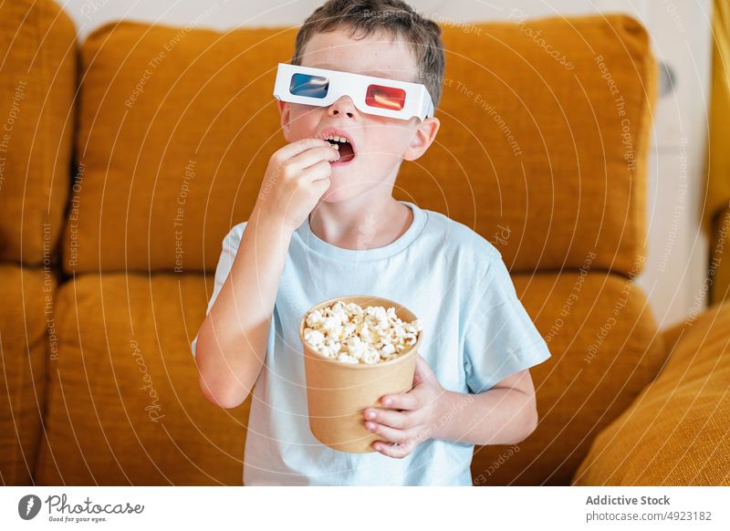 Junge mit 3D-Brille isst Popcorn und sieht sich einen Film an Kind 3d Popkorn zeigen Snack Showtime heimwärts Lebensmittel Inhalt froh Optimist manifestieren