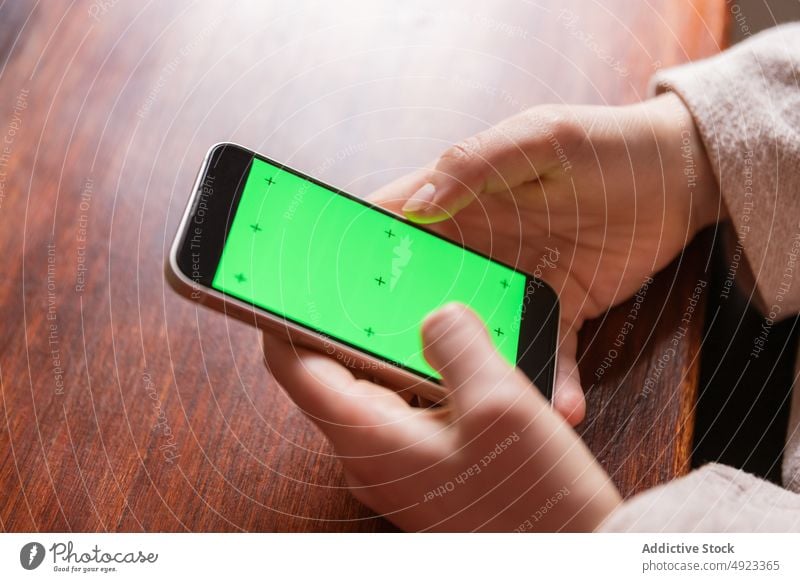 Anonyme Frau beim Surfen auf dem Smartphone mit grünem Bildschirm Browsen online Internet App Talkrunde blättern prüfen benutzend Hand Funktelefon Tisch