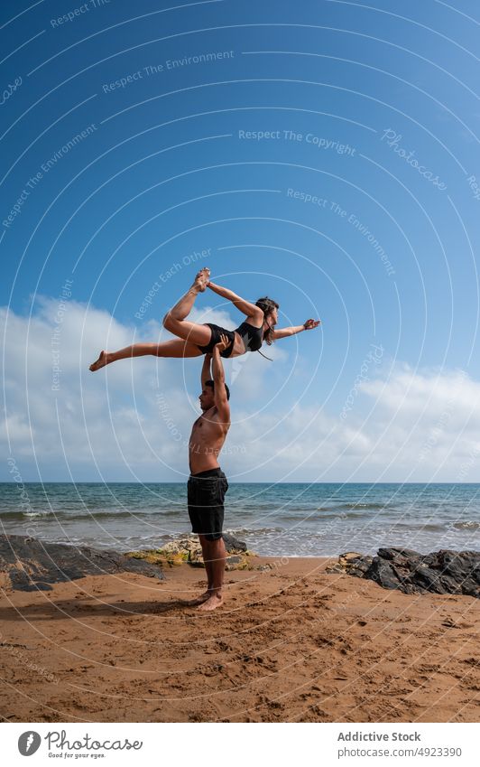 Paar macht Acro Yoga gegen bewölkten Himmel Akro-Yoga Strand Zusammensein Arme hochgezogen MEER Gleichgewicht Sommer üben Asana Mann Frau Energie Wochenende