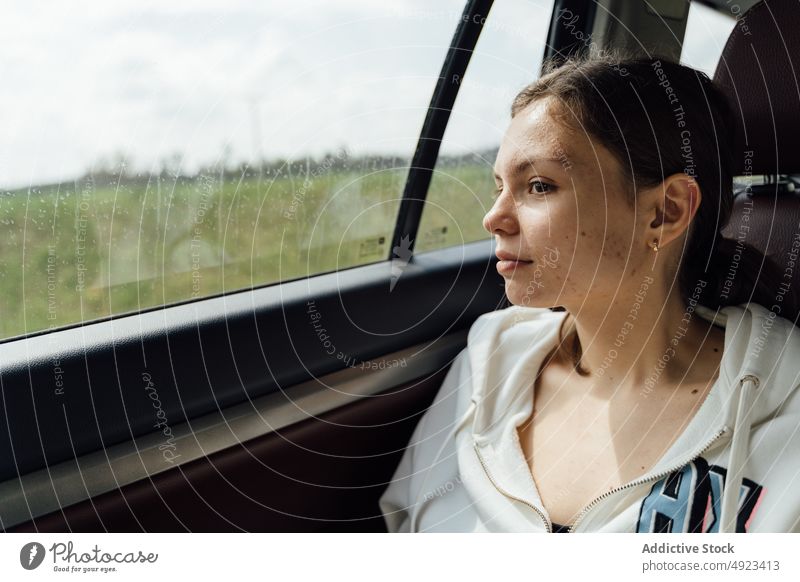 Ruhige junge Beifahrerin im Auto sitzend an einem regnerischen Tag Frau PKW Autoreise besinnlich Ausflug Rücksitz Passagier Windstille Route Reise Regen