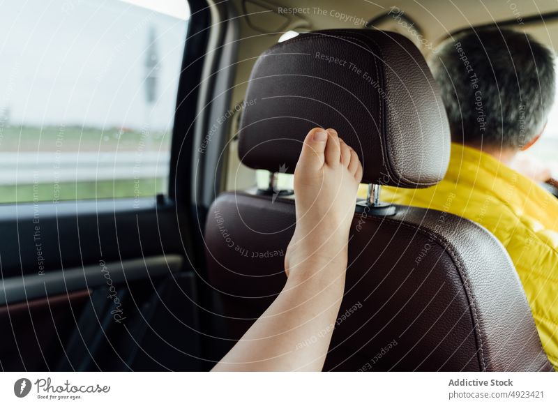 Anonymes Kind lehnt sich mit angehobenem Bein an das Fenster im Auto Bein angehoben PKW Autoreise Passagier sich[Akk] entspannen Fahrzeug Ausflug Straße Verkehr