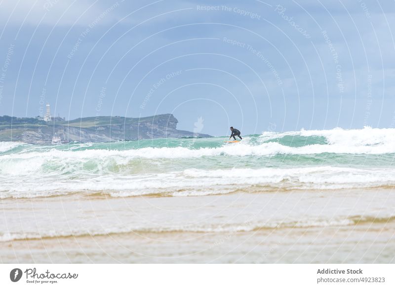 Anonymer Mann reitet auf einer Welle auf einem Surfbrett im Meer Surfer Surfen extrem winken Mitfahrgelegenheit Aktivität üben Hobby Sport männlich Neoprenanzug