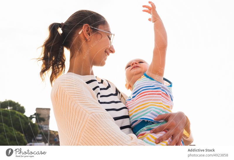 Glückliche junge Mutter, die ihren Sohn umarmt Umarmung Straße Lächeln Liebe Zusammensein Sommer tagsüber Frau Junge Arm angehoben Eltern heiter Mutterschaft