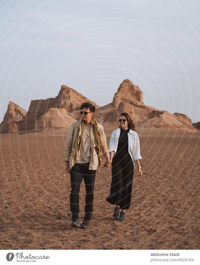 Glückliches reisendes Paar, das sich an den Händen hält und in der Wüste spazieren geht Händchenhalten wüst Spaziergang Ausflug Lächeln Liebe Urlaub Reisender