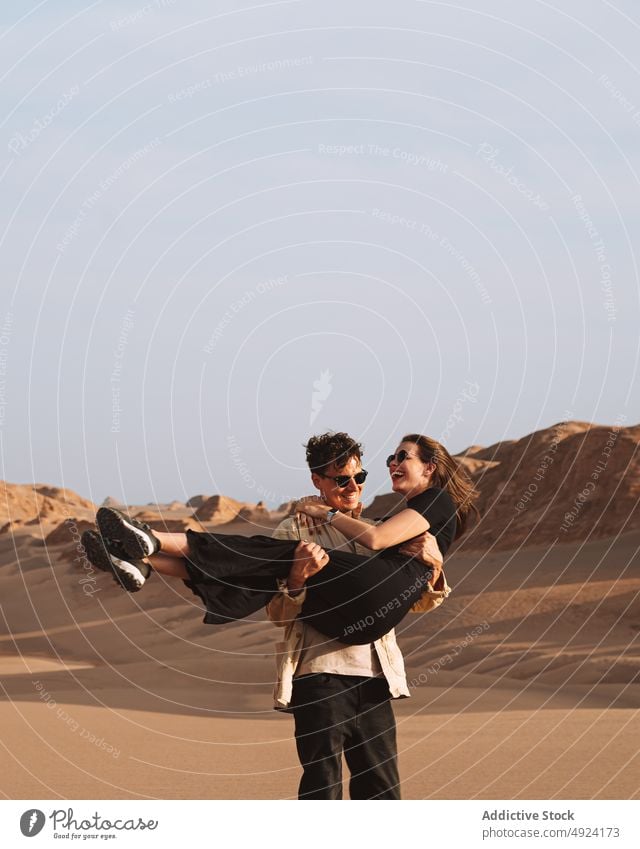 Verliebter Mann umarmt glückliche Freundin während eines Ausflugs in der Wüste Paar wüst Umarmung heben Spaß haben Reisender Liebe Lächeln Glück Partnerschaft
