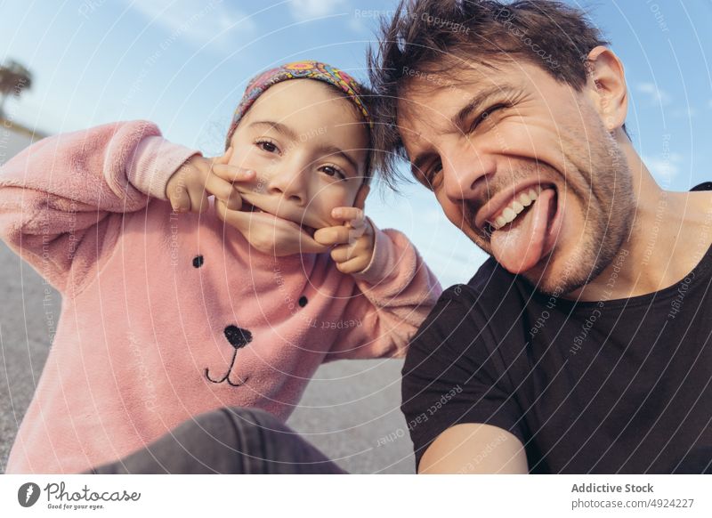 Vater und Tochter schneiden Grimassen und machen ein Selfie Gesicht machen lustig Straße Zusammensein Wochenende spielerisch Zunge zeigen Mann Mädchen Dehnung
