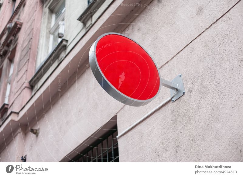 Runde Plakatwand Mockup Bild. Rotes rundes Ladenschild für Logo-Mockup. Ladenschild auf grauem altem Gebäude auf der Straße. blanko Zeichen rot Markenbildung
