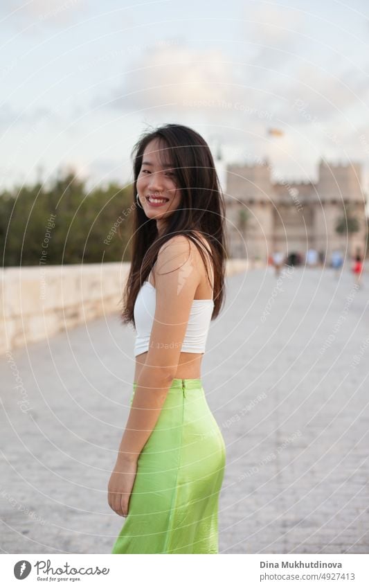 Schöne junge asiatische Frau auf der Straße einer historischen europäischen Stadt. Weibliche Touristin aus China auf Reisen in Europa, lächelnd. Austauschstudentin.