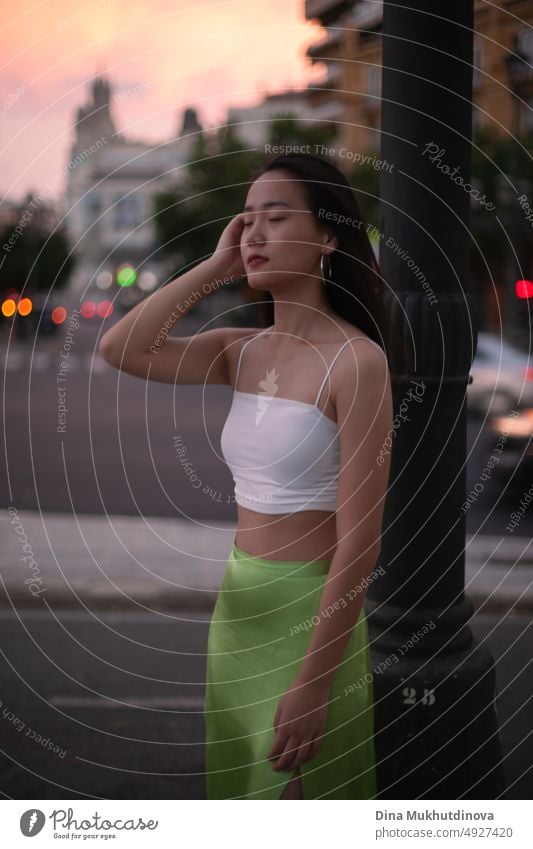 Schöne junge asiatische Frau zu Fuß die Straße der modernen Stadt bei Sonnenuntergang. Weiblicher Tourist aus China auf Reisen in Europa. Mode und Stil Konzept.