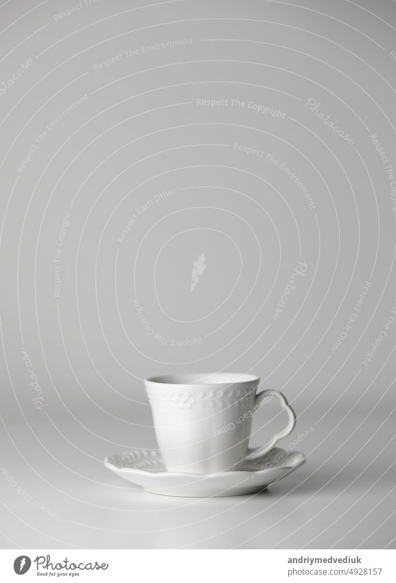 Weiße Teetasse und Untertasse mit einem Muster für Getränk auf weißem Hintergrund. Keramische Kaffeetasse oder Becher Nahaufnahme. Mockup klassischen Porzellan-Utensilien. kopieren Raum