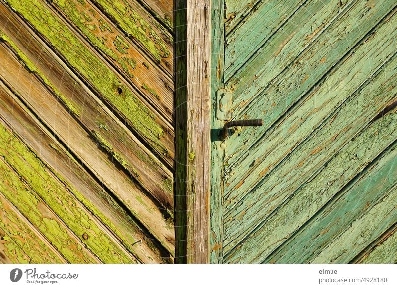 großes Holztor mit schlichter Türklinke, schrägen Holzbrettern und mit unterschiedlich grüner Farbe gestrichen, die abblättert Tor Bretter geschlossen Eingang