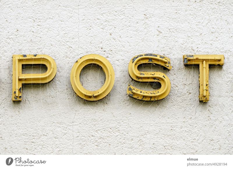 alte, gelbe Leuchtreklamebuchstaben POST an einer Hauswand / Postamt Neonreklame defekt marode traditionelle Post Briefversendung Postschalter Paketversand