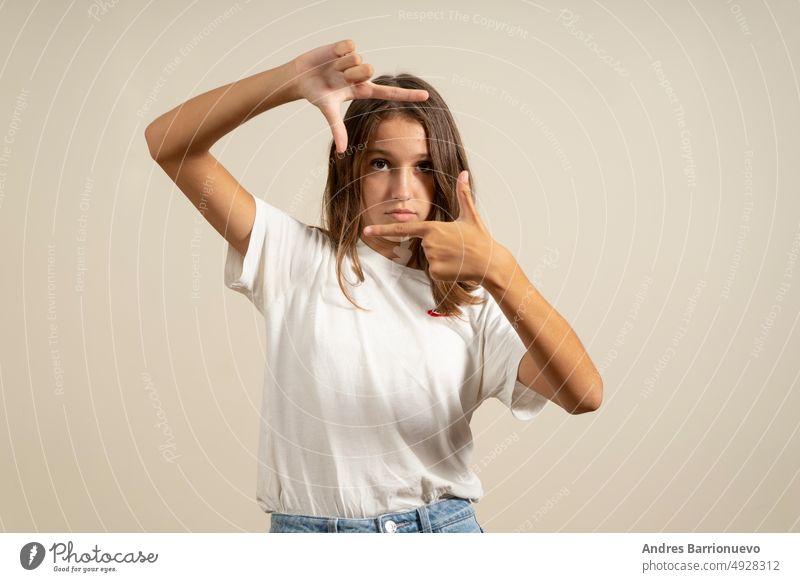 Teenage latin girl wearing casual white t-shirt smiling making frame with hands and fingers with happy face. creativity and photography concept vereinzelt