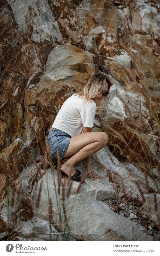Ein wunderschönes blondes Mädchen versteckt sich neben ein paar schweren Felsen. Bekleidet mit blauen Shorts und weißem Hemd. Sie fühlt sich wie im Urlaub. Sie reist herum und erkundet Orte in Vietnam.