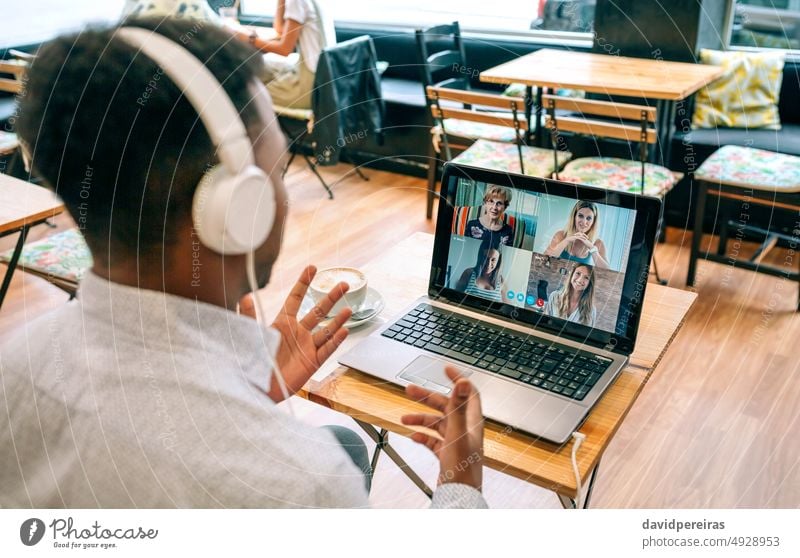 Mann spricht per Videoanruf mit Freunden aus einer Cafeteria unkenntlich sprechend Kaffeehaus Kantine Internet Laptop Kopfhörer online Person Videokonferenz