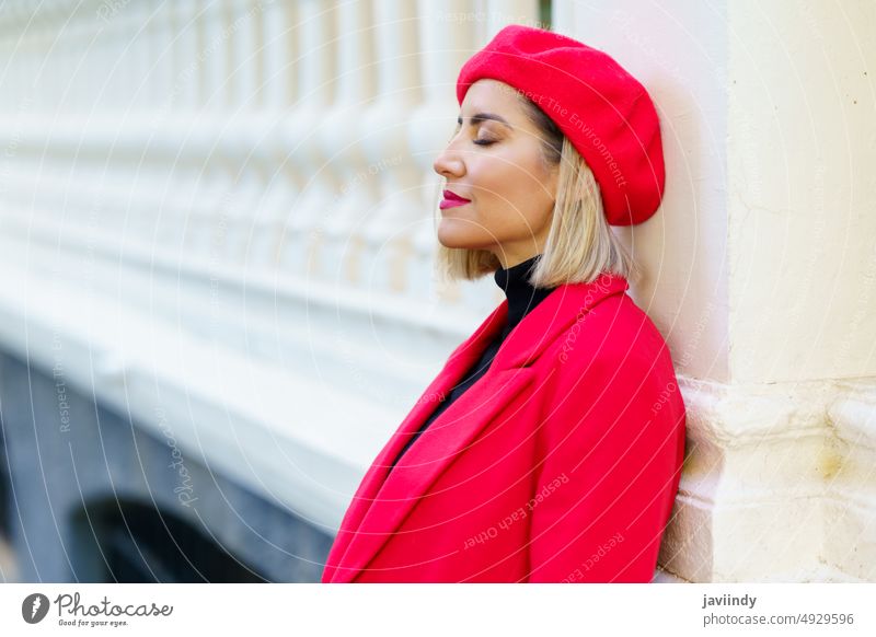 Stilvolle Frau in roter Kleidung in der Stadt Straße Zaun Großstadt Baskenmütze Mode feminin Design Spalte Outfit attraktiv traumhaft Blondine Ständer