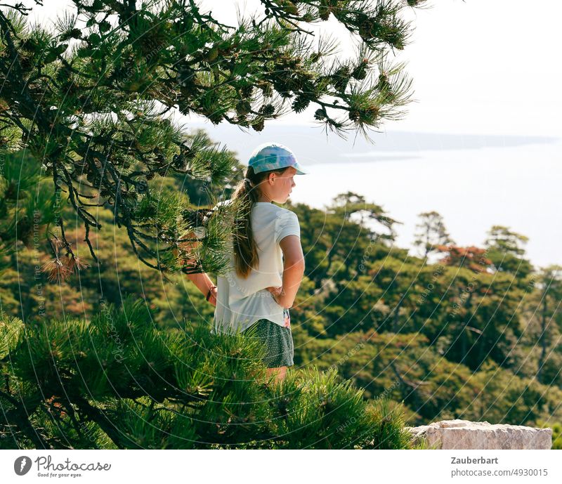 Mädchen beim Wandern unter einer Kiefer, schaut auf das Meer Mütze Basecap grün Natur schauen Urlaub Sommer Baum Wald Erholung