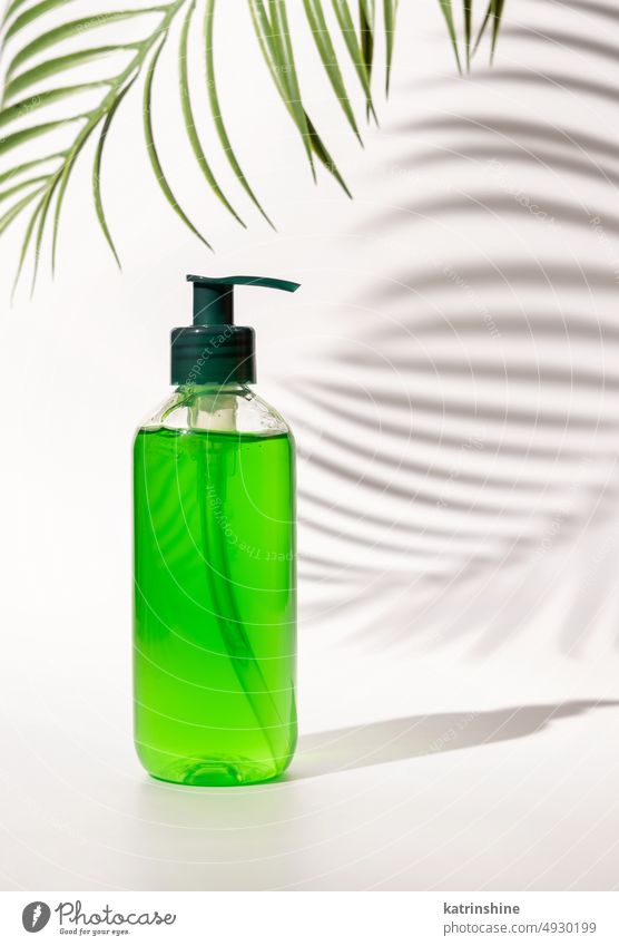 Kosmetische Pumpspenderflasche gefüllt mit grüner Flüssigkeit auf weißem Grund, Palmwedel-Hartschatten Flasche Pumpe rosa Kosmetik Attrappe Handfläche Blatt
