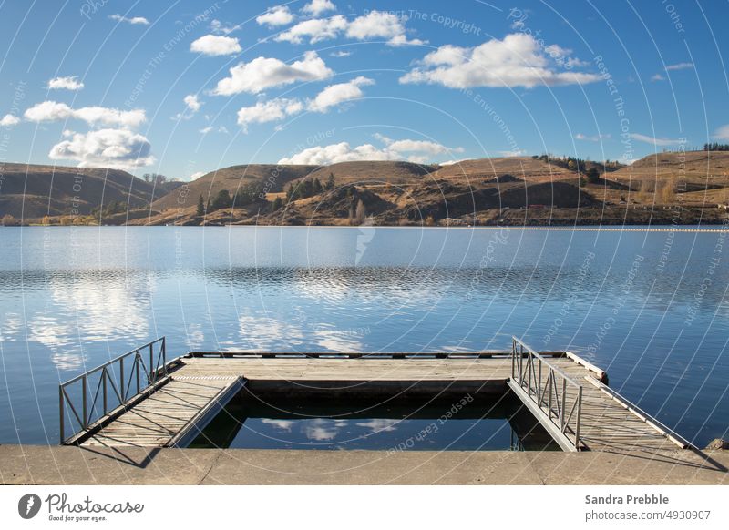 Ein geometrisches Landschaftsbild mit einem Steg, einem See und fernen Hügeln Dunstan-See Sandra Prebble Clyde-Damm Anlegestelle Mittag Feiertag Keiner da leer