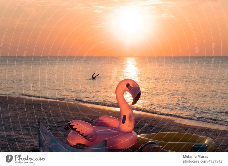 Spaß am Strand. Aufblasbare Schwimmen Rad Spielzeug in Form von rosa Flamingo auf Sonnenuntergang Strand. Kind spielen im Wasser.  Konzept der Sommerferien am Meer. Glückliche Kindheit magische Momente.