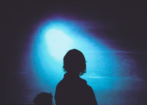 Besucher vor einer blauen Lichtinstallation Projektionsleinwand Mensch Silhouette geheimnisvoll feminin Ausstellung Kunstlicht kunstvoll Profil Schatten