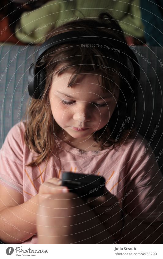 Auf der suche nach einen Hörbuch digital Kind Mädchen Computer Handy mobil Tippen Tablett kabellose Kopfhörer rosa T-Shirt Bus Urlaub Rücksitz zurückgezogen