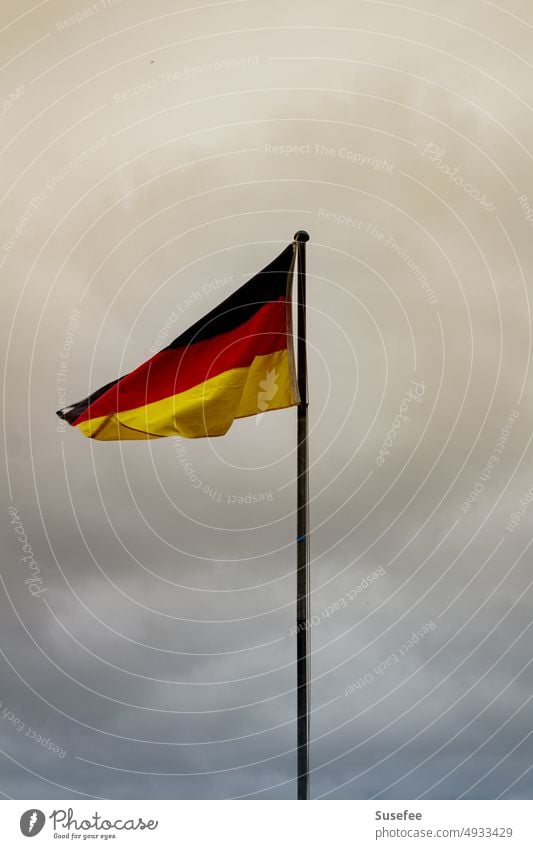 Deutschlandfahne im Wind vor grauem Himmel gelb Heimat Patriotismus Zu Hause Schwarz rot gold Fahne Flagge Germany Nationalflagge wehen