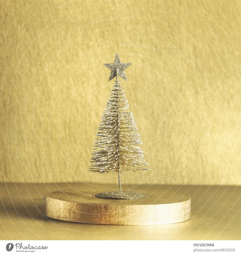 Goldener Weihnachtsbaum auf Podium. Saisonale moderne Winter- und Neujahrskulisse. golden saisonbedingt neue Jahre Hintergrund festliche Dekoration