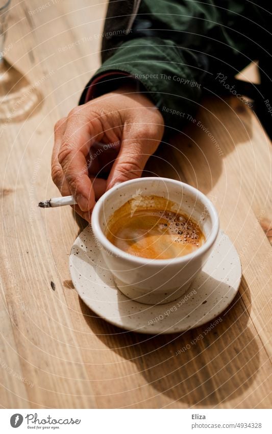 Eine Hand hält einen Espresso und eine Zigarette Kaffee Tasse Espressotasse rauchen Kaffeetrinken Kaffeetasse Nikotin kofein Sucht Drogen Rauchen Kaffeepause