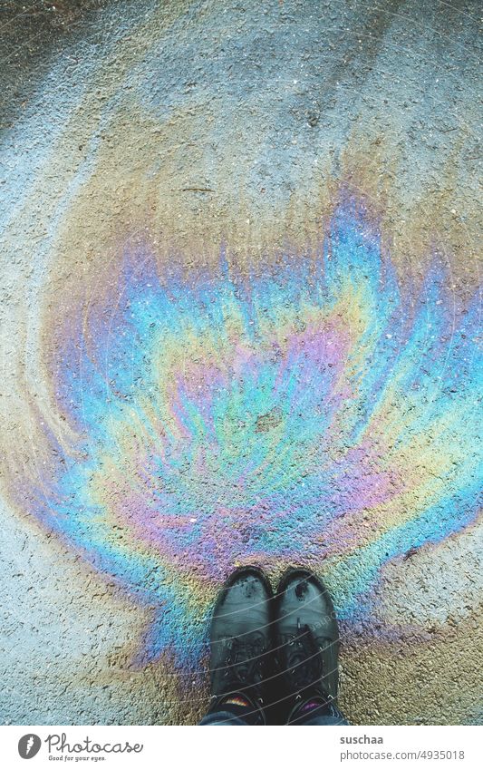 ölfleck auf der straße mit füßen Füße Beine Schuhe stehend Ölfleck Asphalt Straße Umweltverschmutzung Umweltbelastung Ölspur Ölverlust Umweltzerstörung bunt