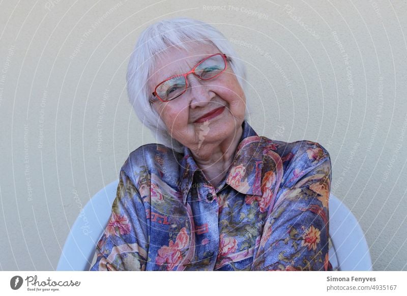 Alte Frau lächelnd 87 Jahre alt Graue Haare Rote Brille rote Lippen Großmutter Portrait Detail Kurzhaar Frisur natürlich Gesicht zufrieden buntes Hemd hübsch