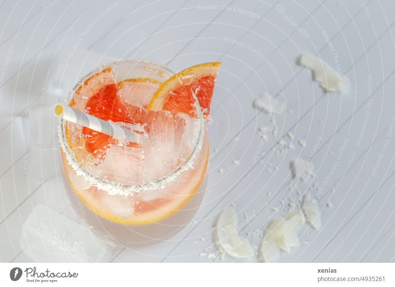 Vitaminwasser mit Grapefruit, Kokosnussraspeln am Glasrand und Eiswürfel mit Trinkhalm Getränk Erfrischungsgetränk Limonade orange weiß Kokosraspeln Detox Diät
