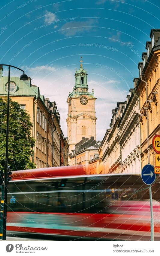 Stockholm, Schweden. Roter Bus in Bewegung Unschärfe Fahrten in der Nähe der Altstadt mit Turm von Storkyrkan - die große Kirche oder Kirche von St. Nikolaus. Der Stockholmer Dom ist die älteste Kirche in Gamla Stan