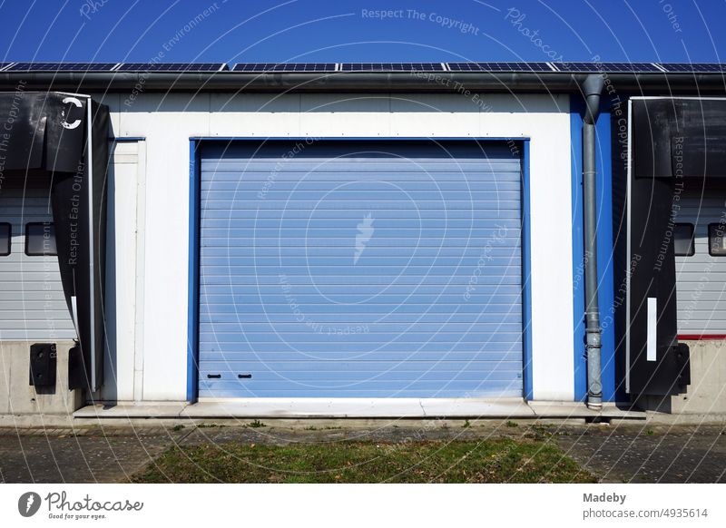 Blaues Rolltor und Industrietor einer großen Lagerhalle vor blauem Himmel im Sonnenschein in Ibbenbüren im Kreis Steinfurt in Westfalen Nordrhein-Westfalen NRW
