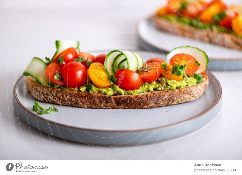 Toast mit Kirschtomaten und Avocado Zuprosten gestampft cucucmber Avocado-Toast Brot Mikro-Grün Mittagessen Frühstück frisch Lebensmittel Vegetarier Gesundheit