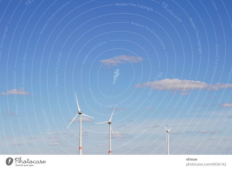 drei Windräder vor blauem Himmel mit einzelnen Schönwetterwolken / Windenergie Windrad Windkraftanlage erneuerbare Energie Ökostrom grüner Strom Strompreis