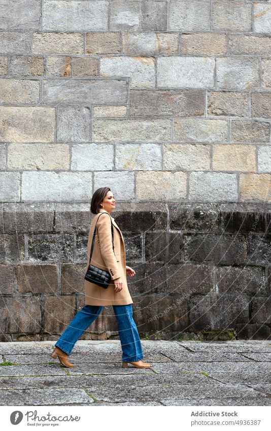 Stilvolle Frau geht auf der Straße Spaziergang Straßenbelag Haus alt smart lässig Gebäude urban Fußgänger Bürgersteig brünett gealtert Stadt schlendern Struktur