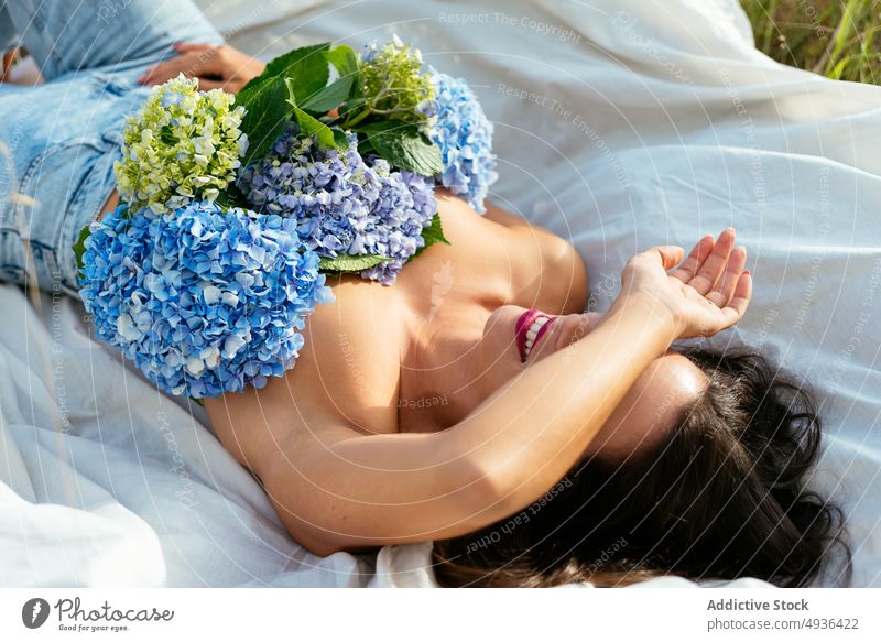 Lächelnde Dame auf Decke liegend mit Blumen auf nackter Brust in der Natur Frau Lügen Augen abdecken Hortensie Verlockung Glück Deckbrust sich[Akk] entspannen