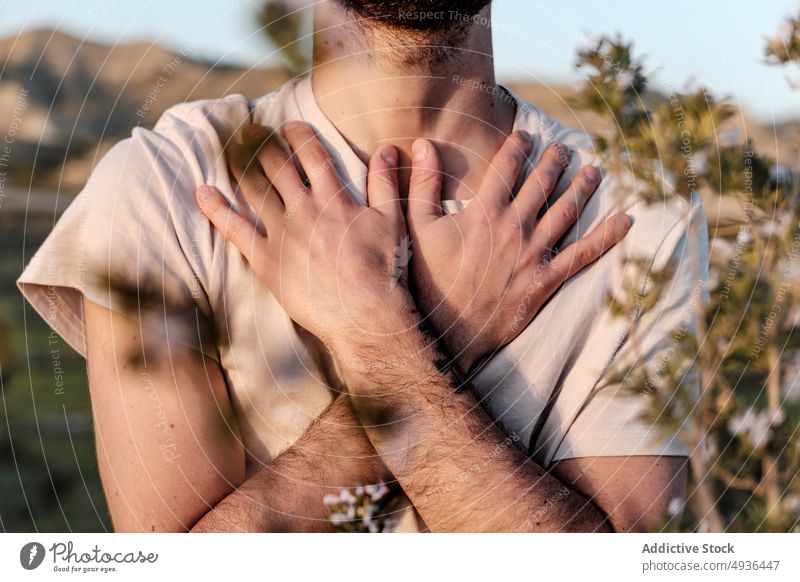 Crop Mann verschränkt Arme auf der Brust meditieren die Arme verschränkt Landschaft Windstille Yoga Sommer ruhen Wochenende Natur männlich Pflanze T-Shirt Truhe