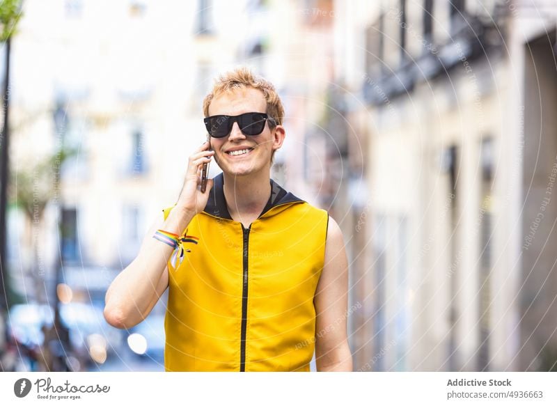 Lächelnder stilvoller nicht-binärer Mann, der auf der Straße mit einem Smartphone spricht nicht binär Stil urban sprechen heiter Freude reden Transgender