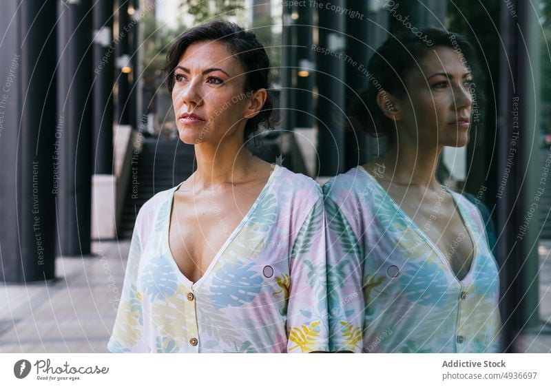 Frau steht in der Nähe eines Gebäudes Straße Großstadt Glaswand Reflexion & Spiegelung Vorschein feminin Stil urban trendy Freude genießen Outfit Vergnügen