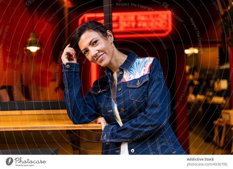 Zufriedene Frau steht in der Nähe eines Cafés Straße Großstadt Stil Vorschein feminin urban Gebäude Mode froh positiv Kantine Lächeln sich auf die Hand lehnen