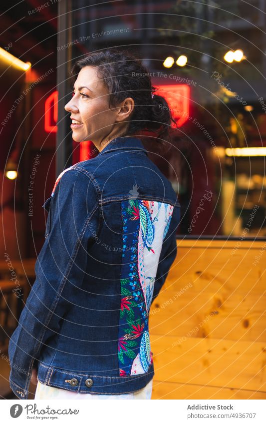 Frau steht in der Nähe eines Cafés auf der Straße Großstadt Jeansstoff Stil Muster drucken feminin Mode urban Vorschein Gebäude traumhaft anhaben dunkles Haar
