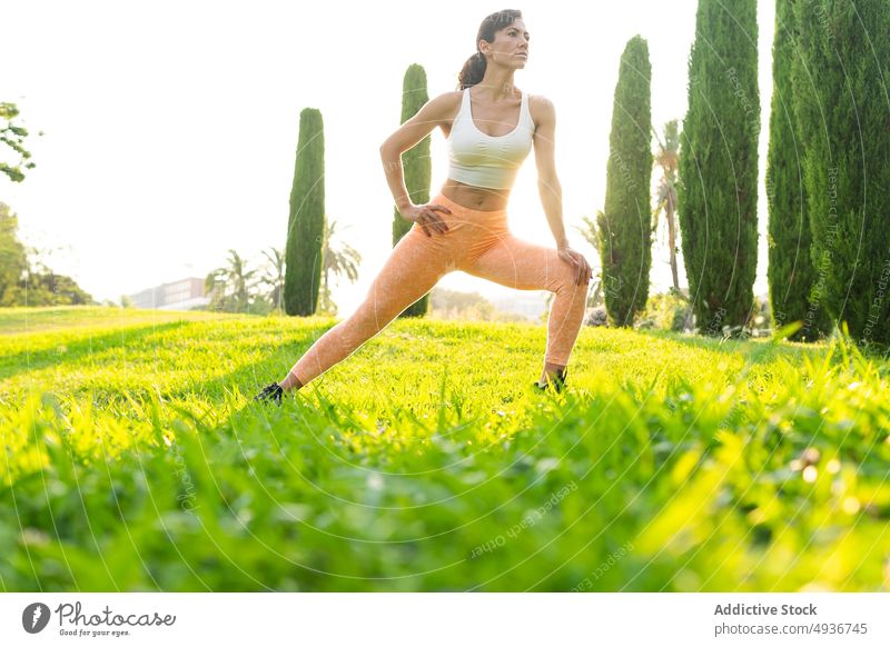 Fit Frau streckt Beine auf Rasen Training Aufwärmen Dehnung Sport Park Übung Fitness üben ernst Windstille Ausdauer beweglich Gesunder Lebensstil Form Gras Feld